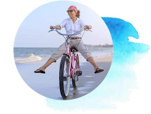 Women riding a bike on beach.